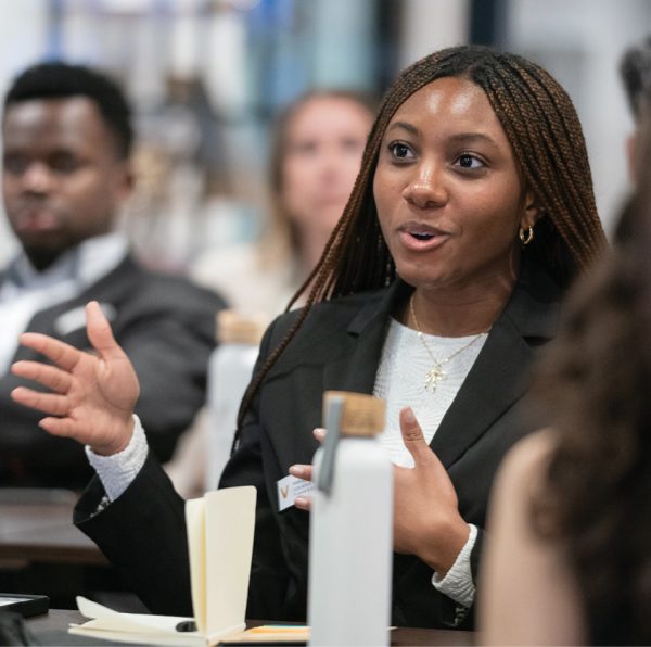 A young woman in business attire participates in a discussion.