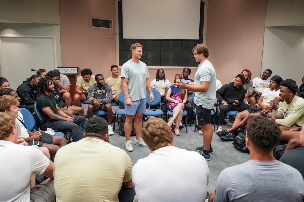 Students stand in the middle of a group speaking to each other