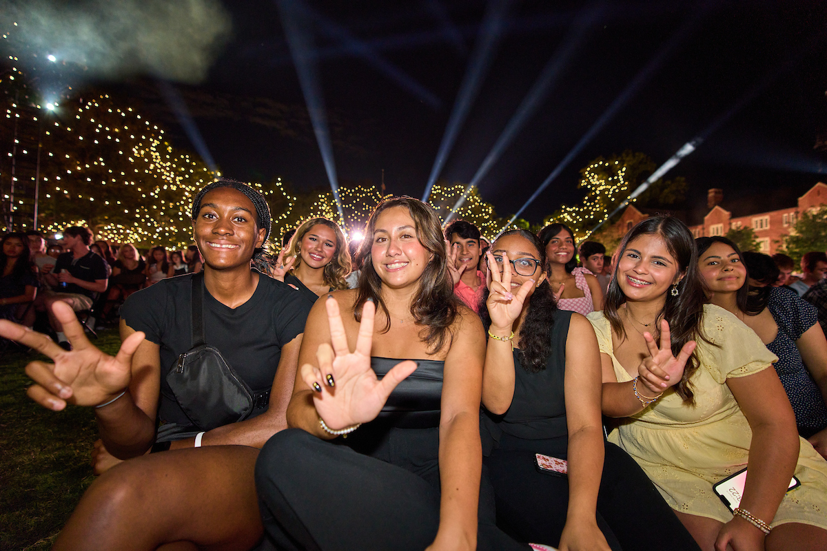 Seated students smile and flash the Vanderbilt sign with their hands