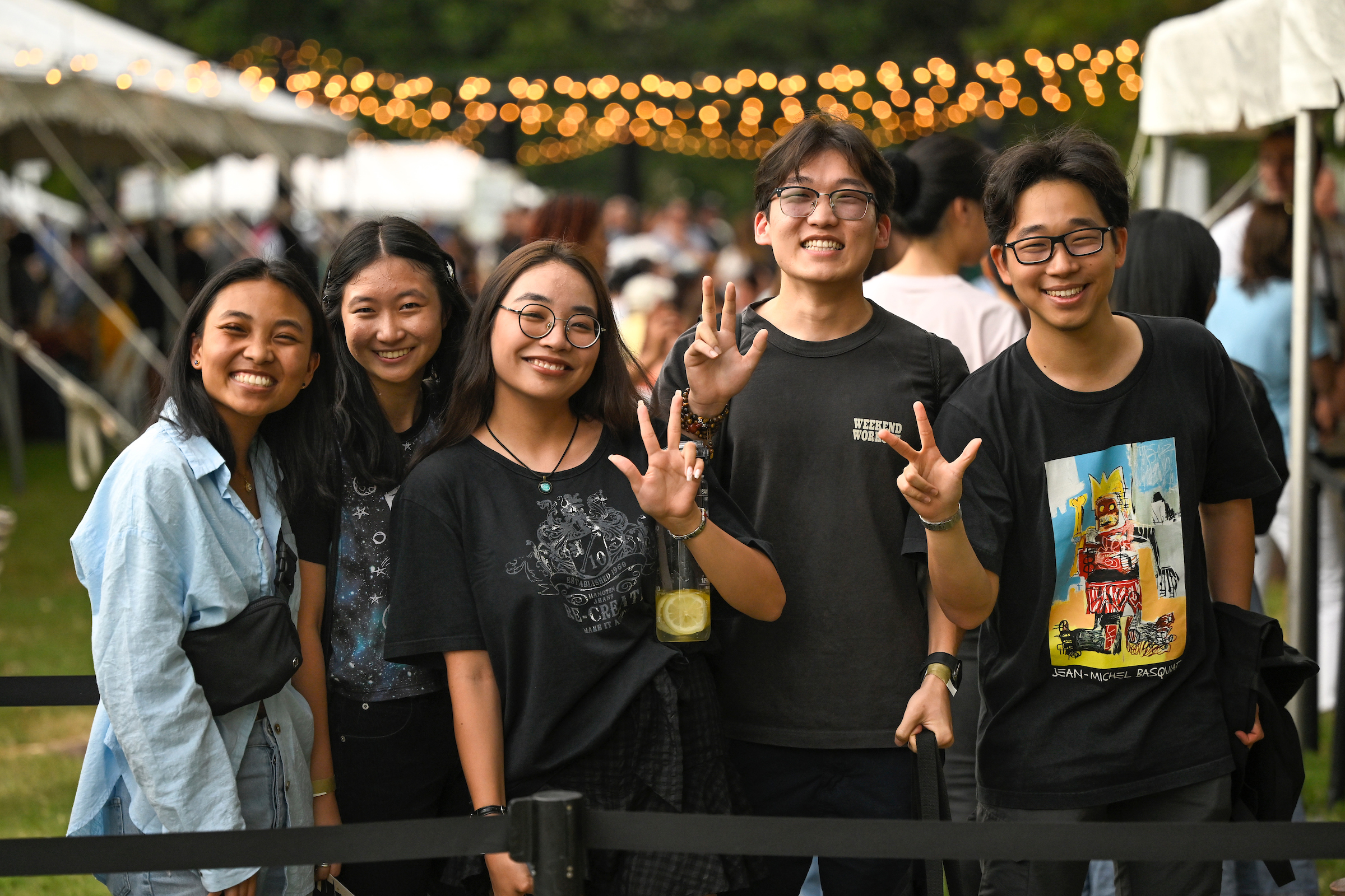 A group of five students stand side-by-side and flash the Vanderbilt sign with their hands. 