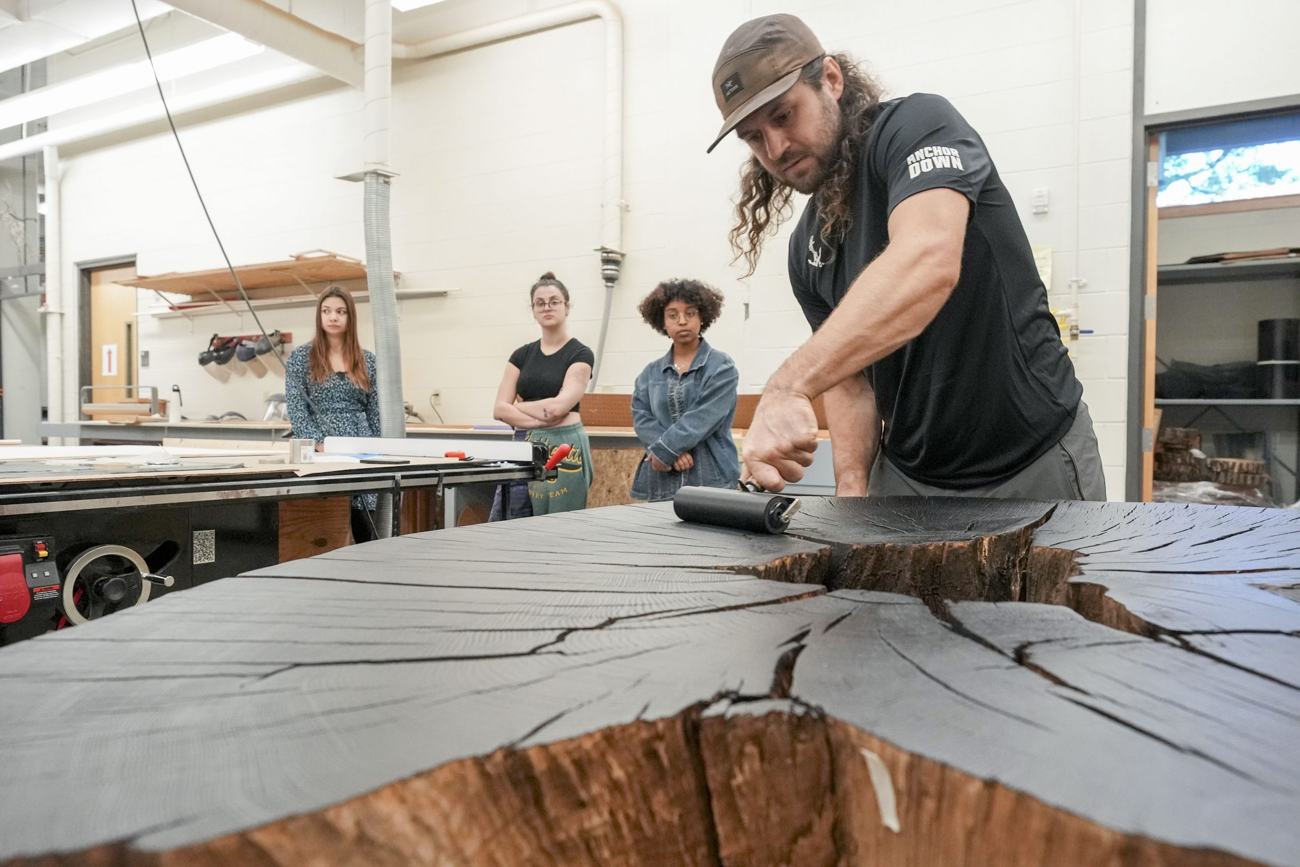 Art students watch as Artist Marko Barakoski makes tree prints at  Ingram Fine Arts studio using the wood from the Bicentennial Oak that fell on campus in 2022.