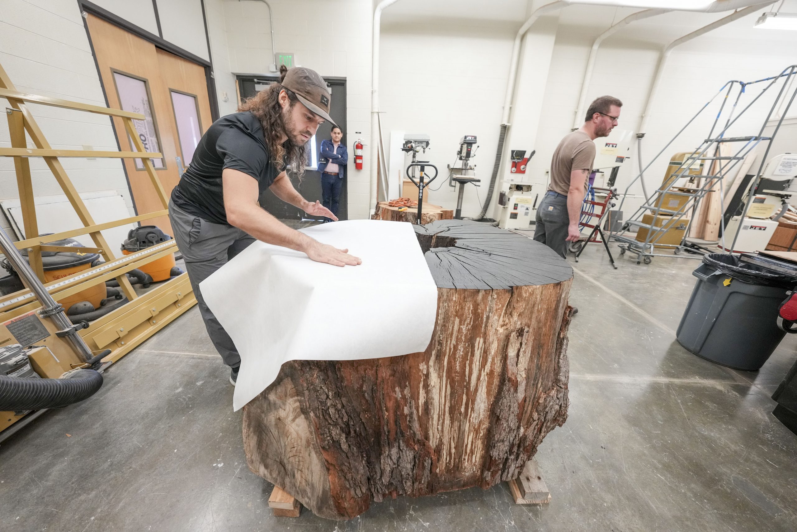 Art students watch as Artist Marko Barakoski makes tree prints at  Ingram Fine Arts studio using the wood from the Bicentennial Oak that fell on campus in 2022.