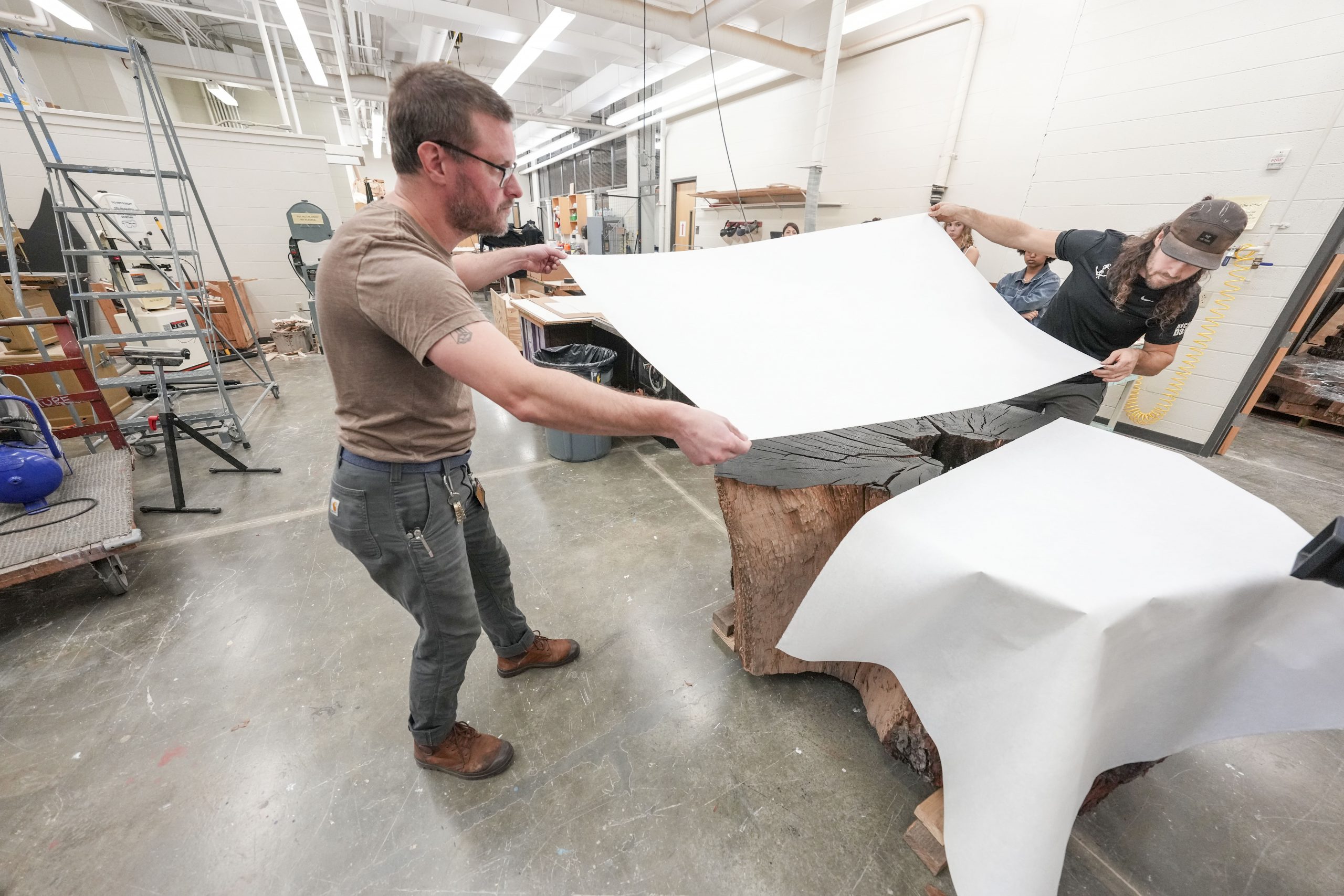 Art students watch as Artist Marko Barakoski makes tree prints at  Ingram Fine Arts studio using the wood from the Bicentennial Oak that fell on campus in 2022.