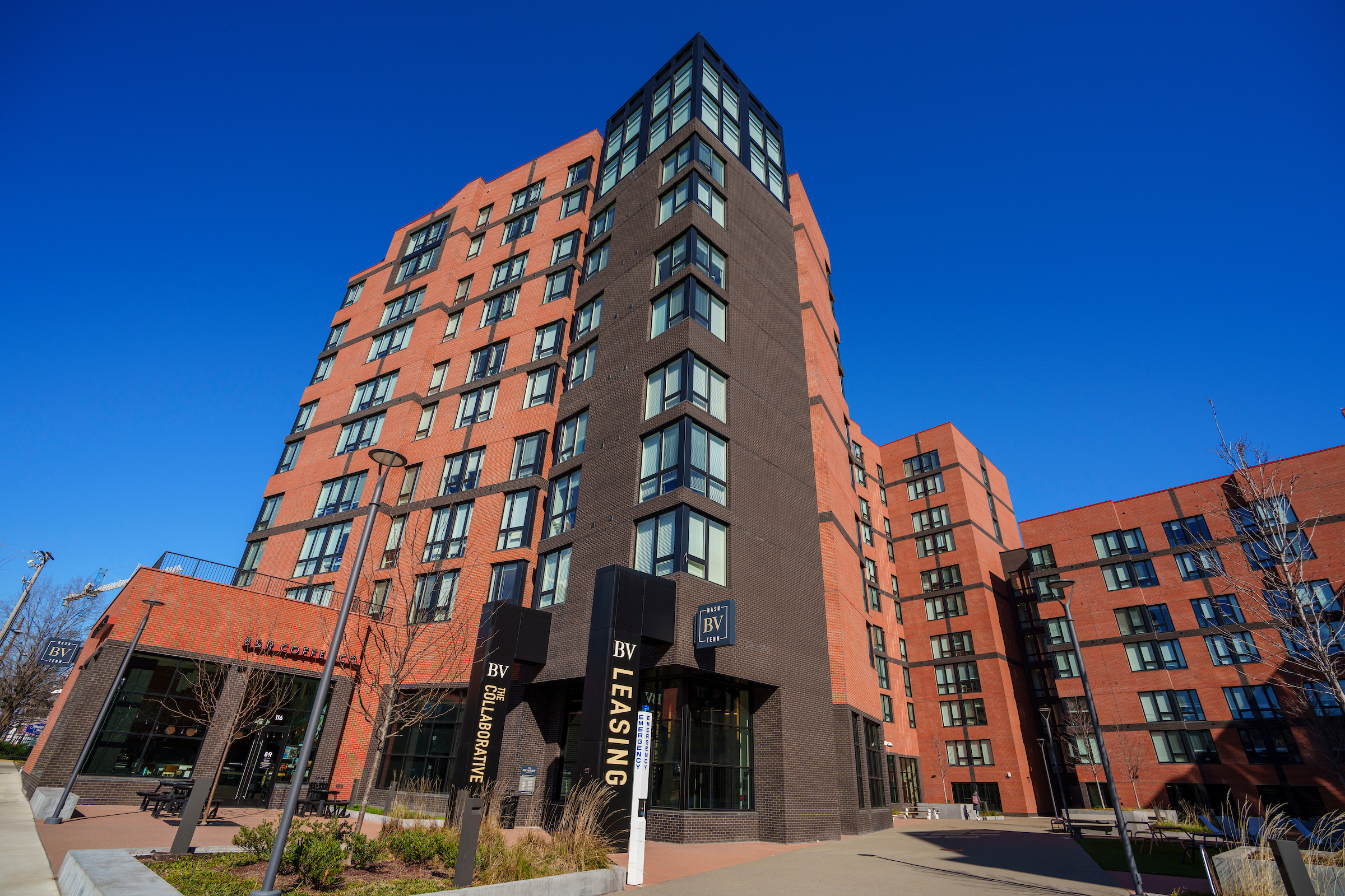 The tall red brick building on the corner of a street