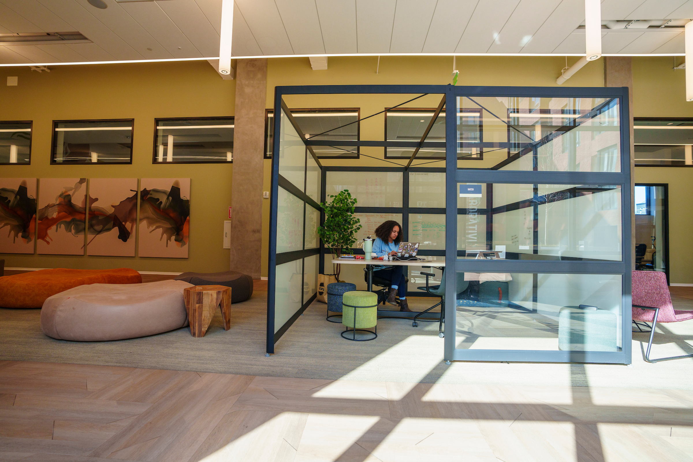 A glass-enclosed cubicle with a student studiying inside.