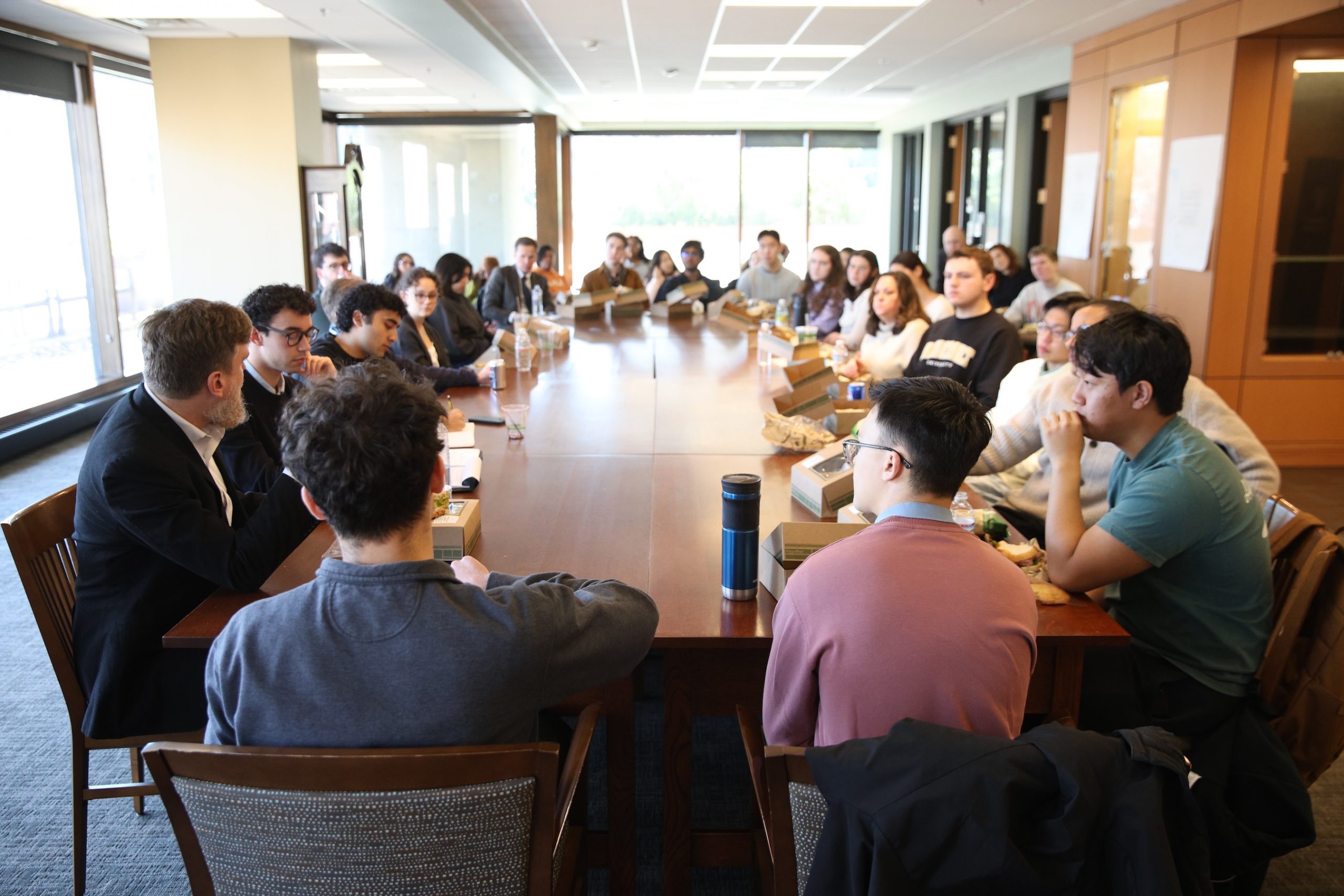 A group of students seated around a long wooden table in a classroom