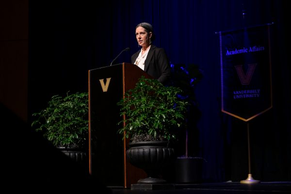 A woman standing before a podium in an auditorium