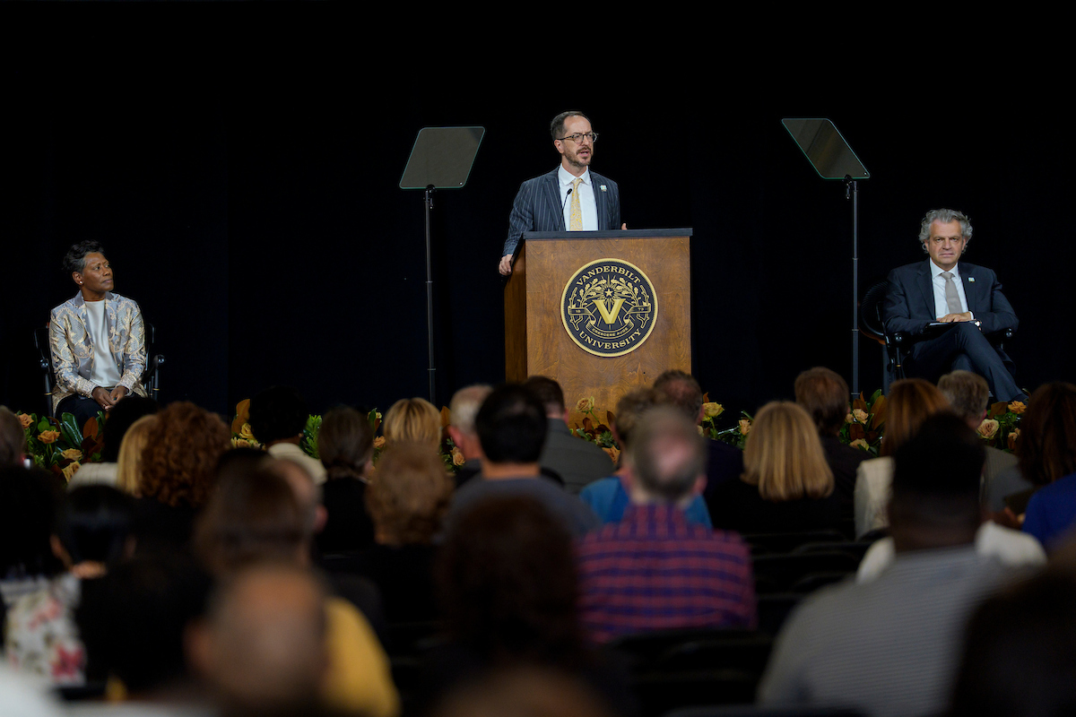 A man standing a podium speaking to an audience