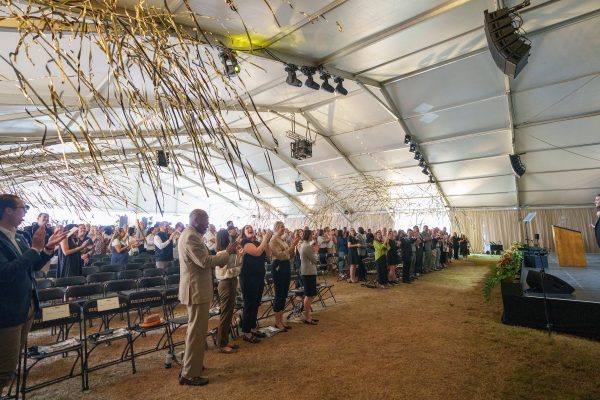 black and gold streamers fall on a crowd under a tent