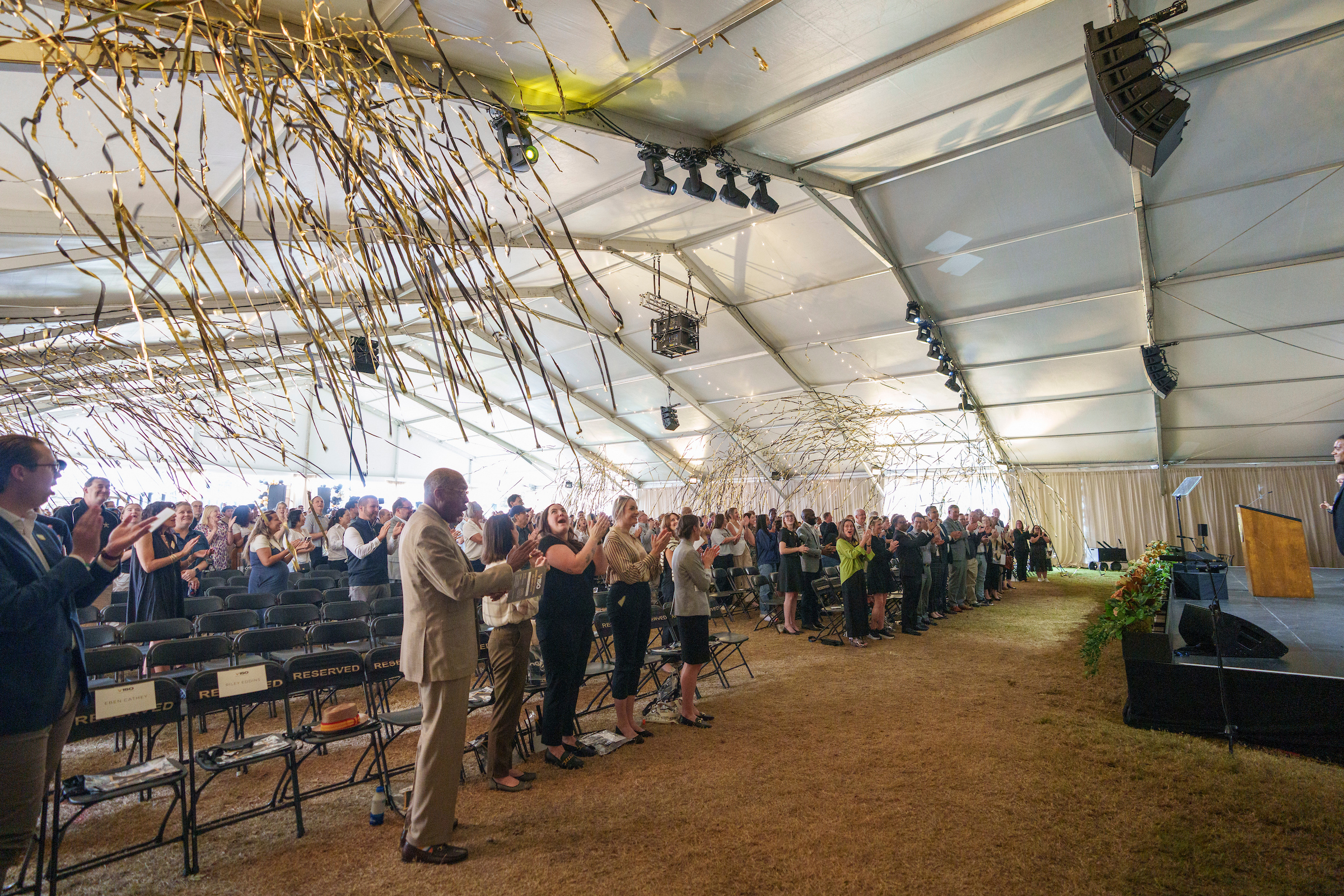 black and gold streamers fall on a crowd under a tent