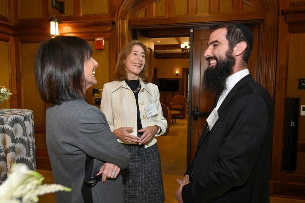 A man and two women share a laugh in a wood-lined room