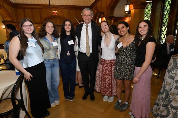 a man stands in the middle of a group photo with female students