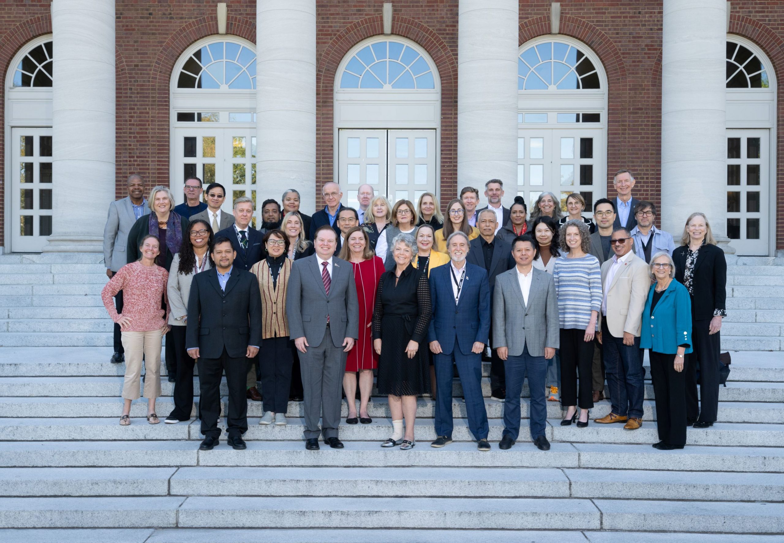 A large group of Global Education Deans' Forum attendees stands on the steps of a Vanderbilt Peabody building.