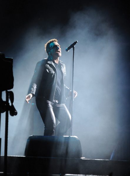 Lead singer of U2 Bono sings into microphone