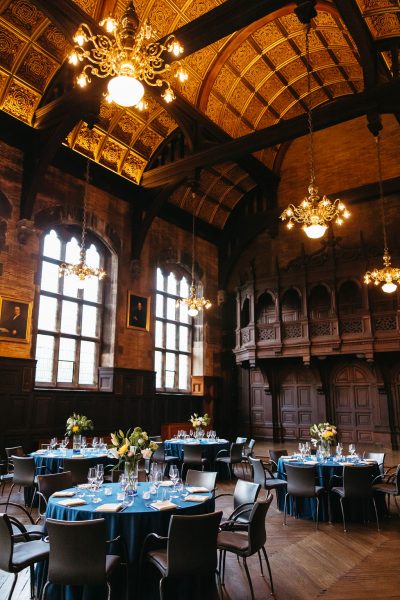 Round tables with place settings assembled in a grand hall.