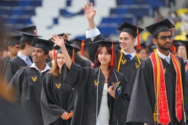 Group of students in black graduation gowns waving