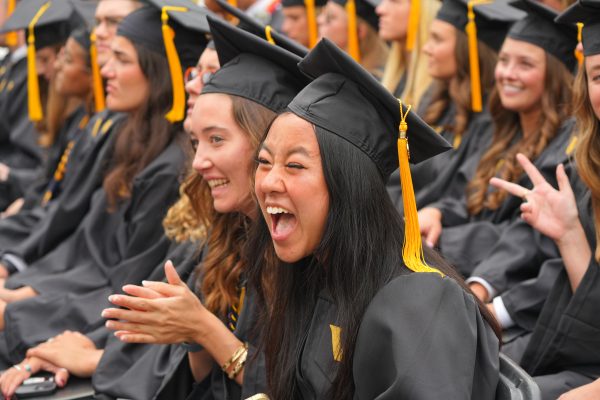 student in black gown and mortar laughing