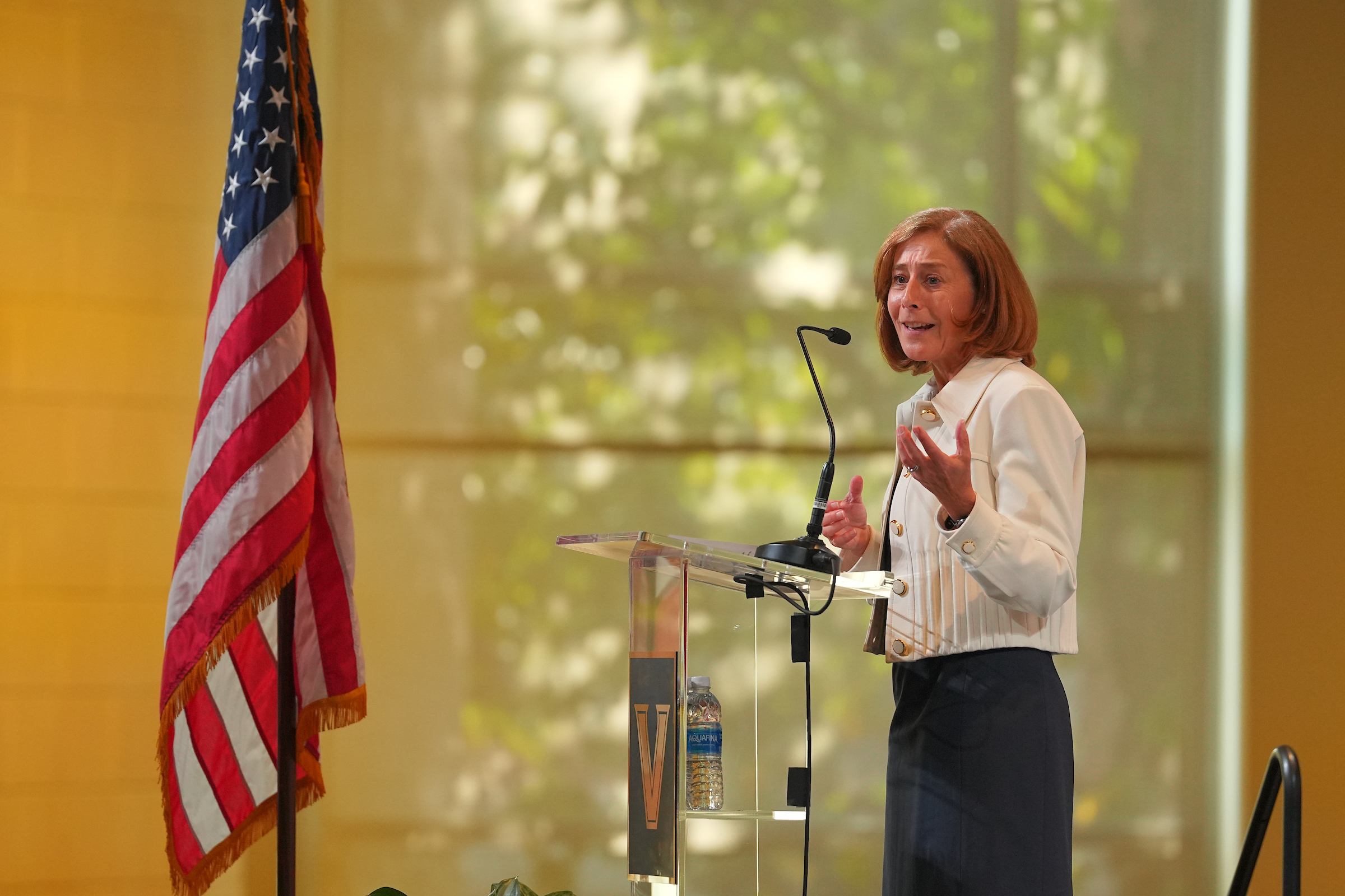 C. Cybele Raver speaking at a podium flanked by the U.S. flag