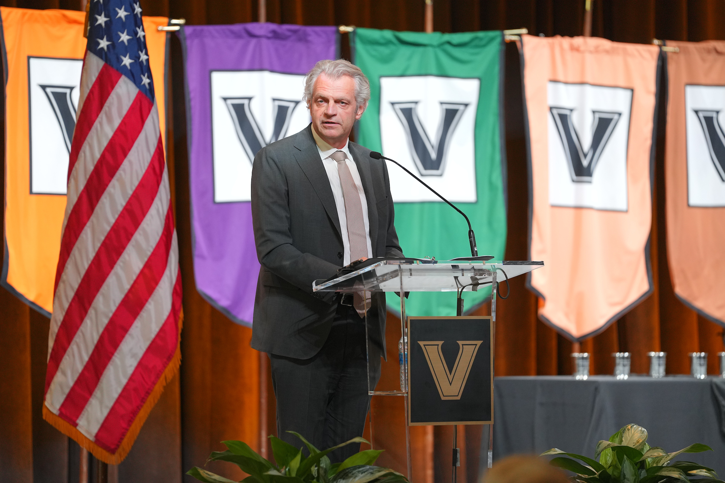 Chancellor Daniel Diermeier speaks at a podium with multicolored Vanderbilt banners behind him.