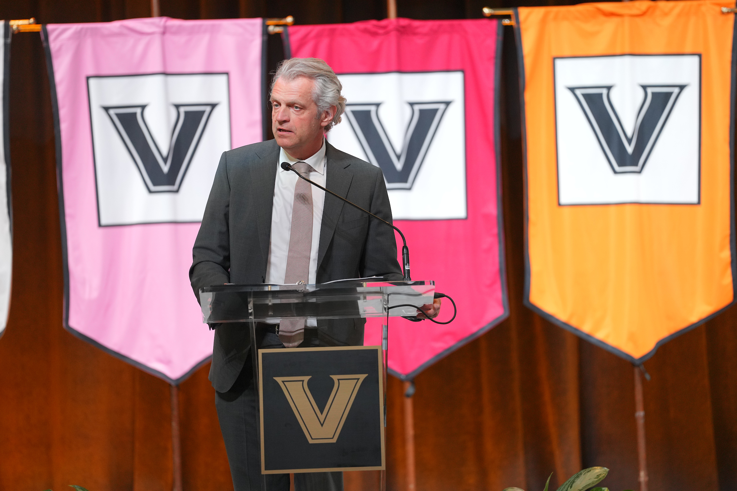 Chancellor Daniel Diermeier speaks at a podium with multicolored Vanderbilt banners behind him.