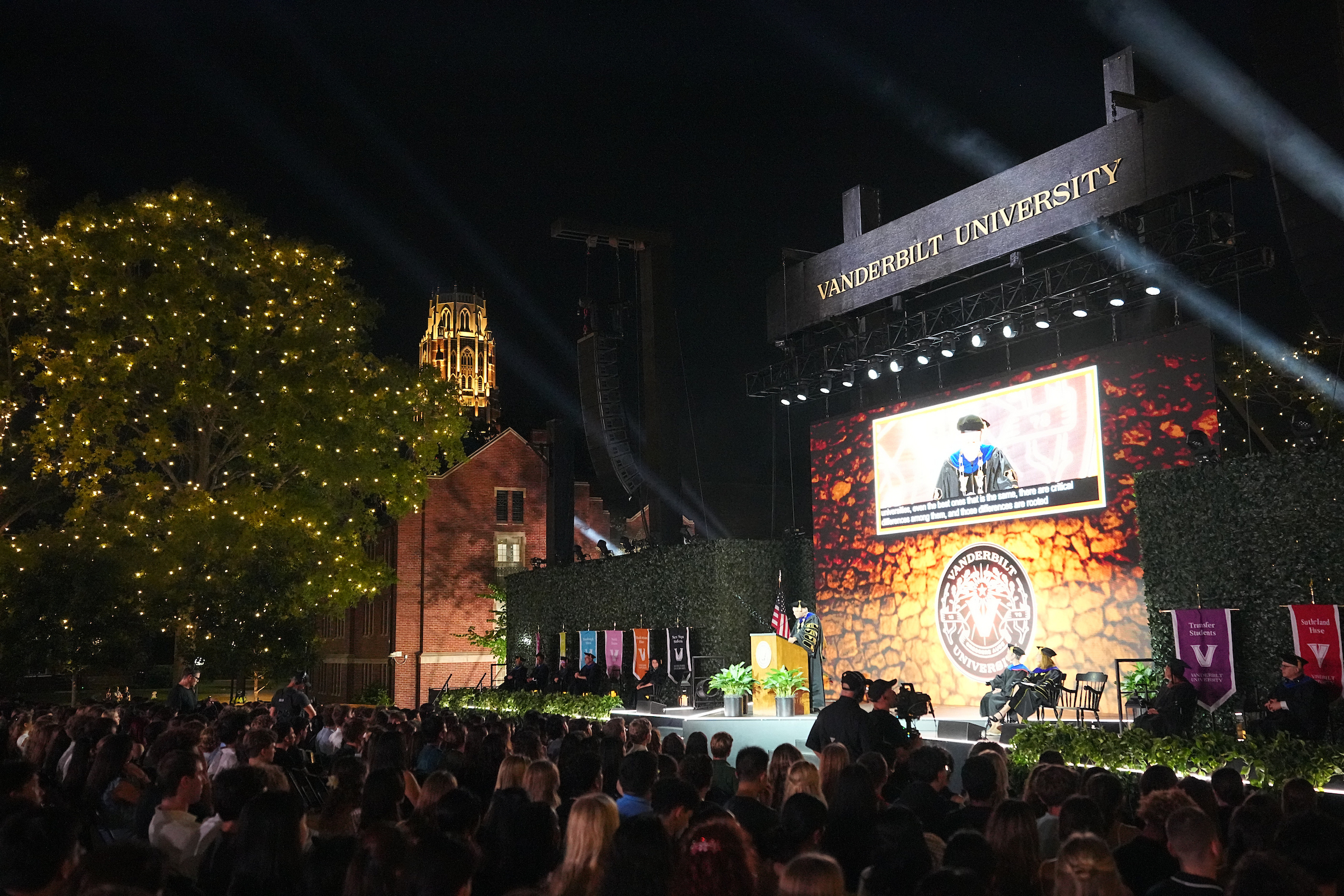 An overview of a stage and filled seats outside at night