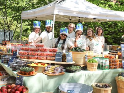 Seven workers at the Rand Farmers Market surrounded by produce