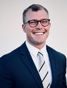 Man wearing glasses, blue suit and white collared shirt