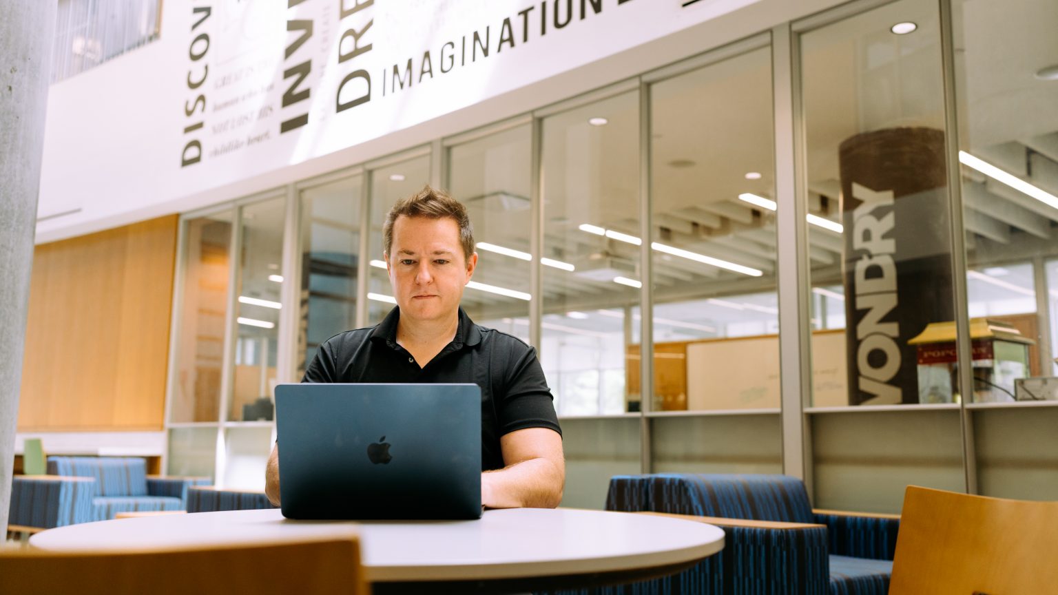 A man sits before a laptop on a desk.