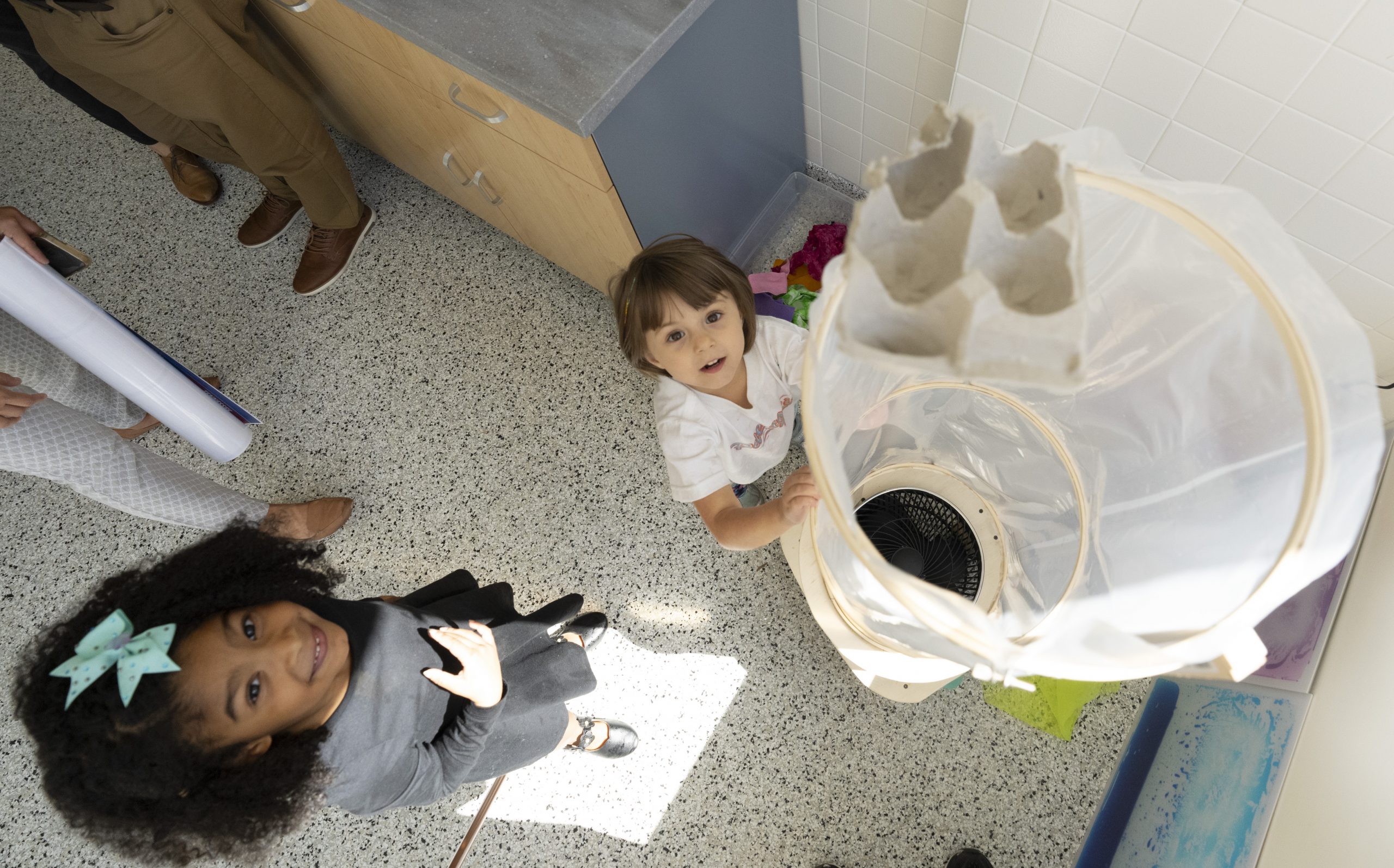 Two young girls playing with a wind tunnel in a preschool STEM lab