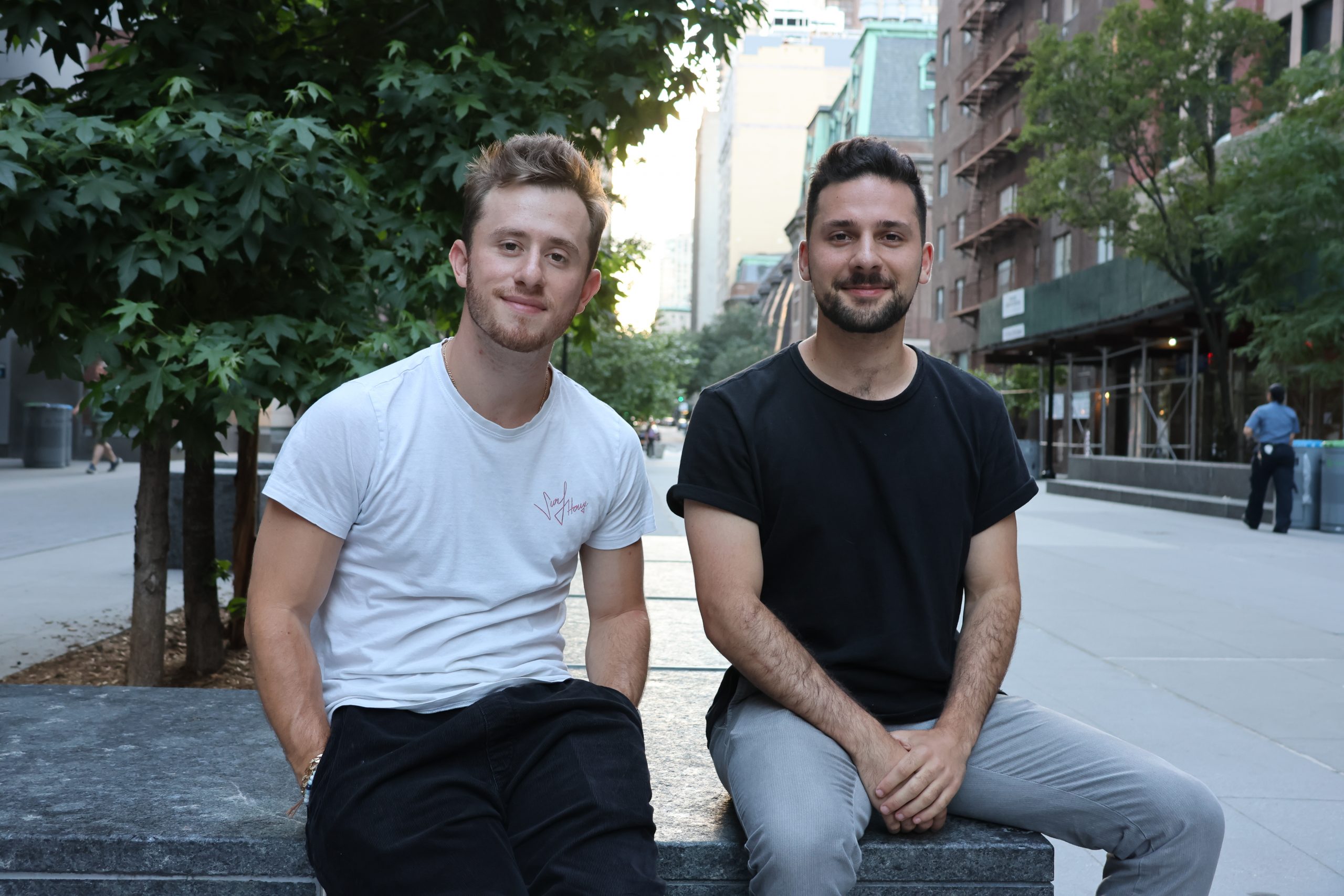 Two young men sitting on a bench in a city