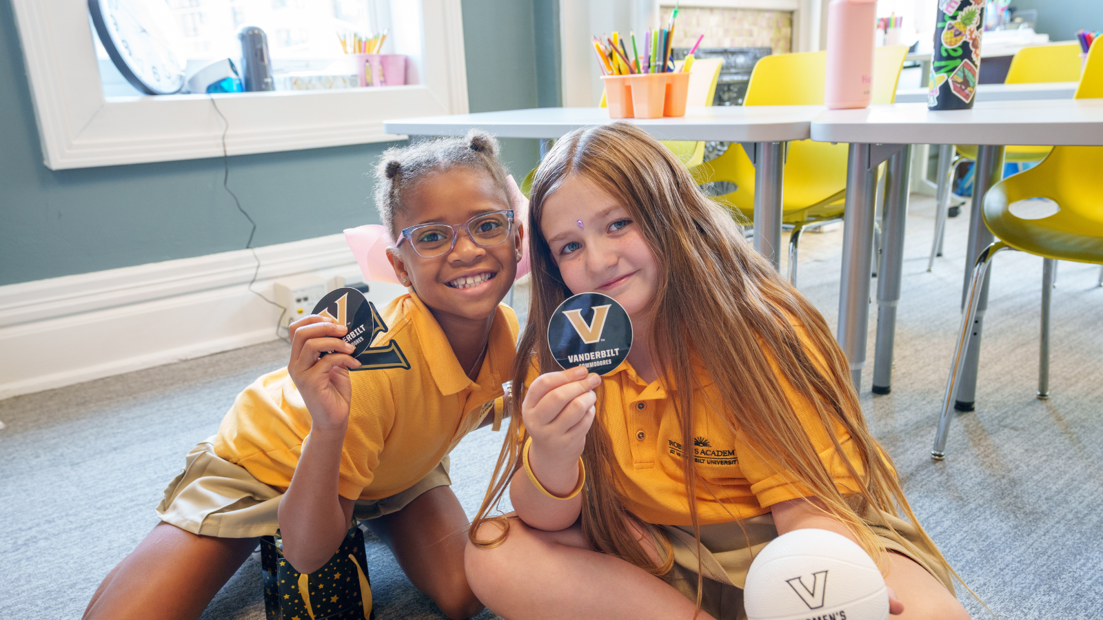 Two female students at the Roberts Academy holding up Vanderbilt stickers.