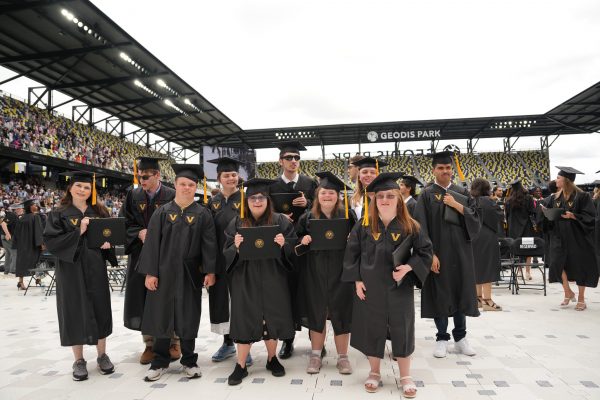 A group of students are standing in graduation caps and gowns at their graduation ceremony.