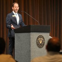 Vice Provost Alex Sevilla speaks to a crowd from a podium