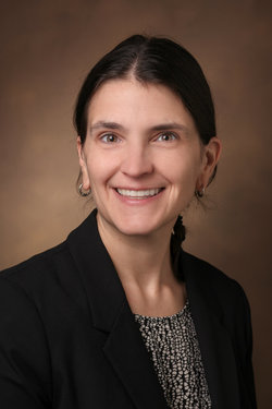 woman with brown hair in black suit jacket and blouse