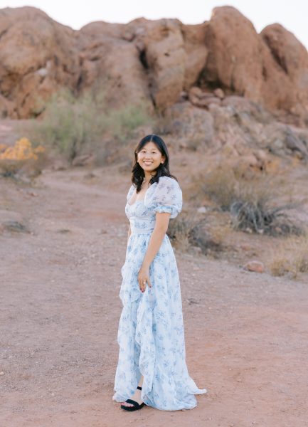 A young woman in a light blue dress in a desert setting with rocks behind