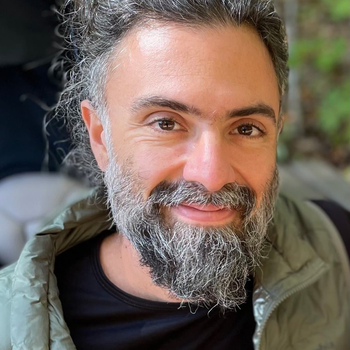 A close-up portrait photo of a bearded man smiling. 