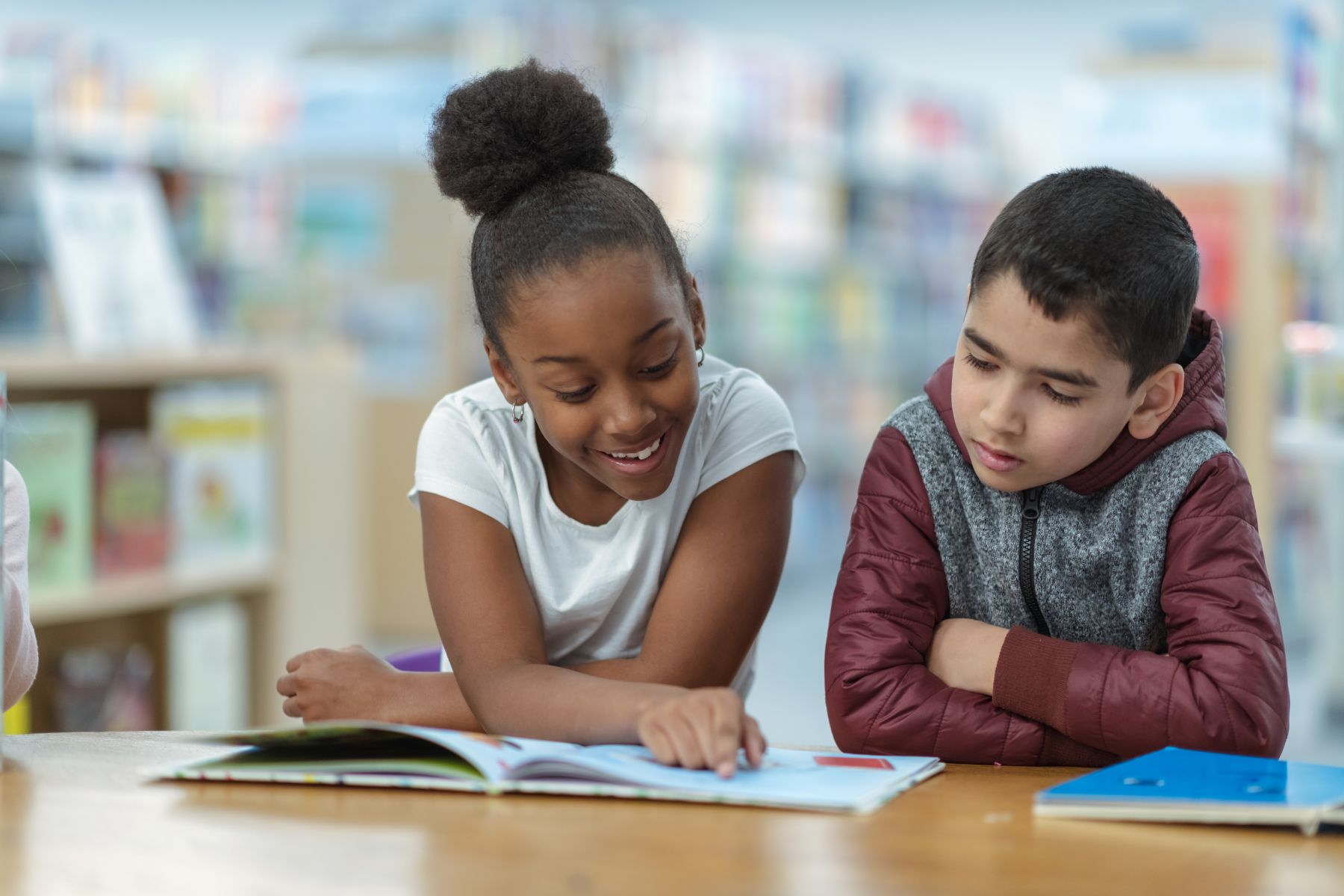 Girl and boy look at a book together