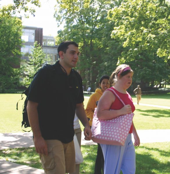 Two students walk across campus carrying bookbags.