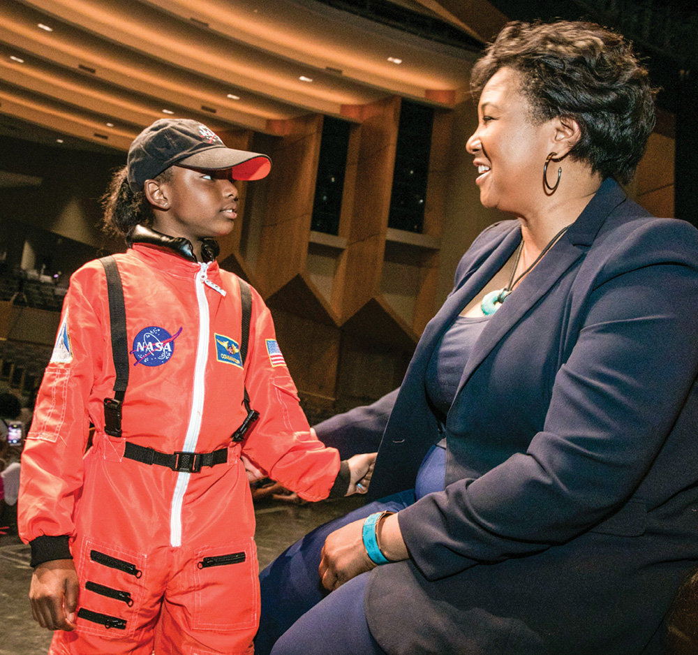 photo of Mae Jemison with a young girl dressed in an astronaut jumpsuit