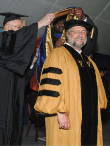 Caruso is hooded by Centennial Professor of Philosophy John Lachs, left, as he receives his Ph.D. in philosophy in May 2016.