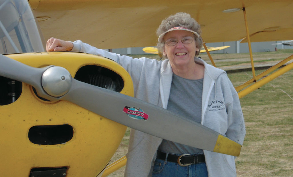 Rickman stands with an Aeronca Champ, the plane in which she learned to fly, training on a grass runway. The single-engine Champ is very similar to the trainer airplane the WASP first learned to fly. Photo courtesy of Sarah Byrn Evans Rickman