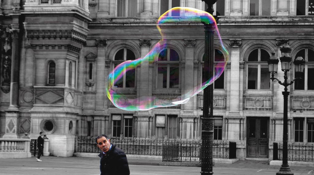 photo of man looking at giant soap bubble
